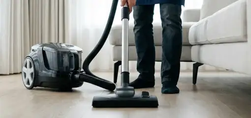 Professional house cleaner vacuuming a living room floor with a canister vacuum cleaner, Austin, TX.