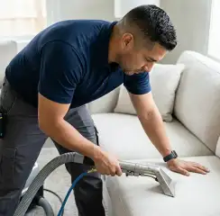 Professional upholstery cleaning technician using an extraction wand to deep-clean a fabric sofa, Austin, TX.