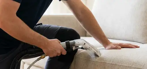 Professional upholstery cleaner deep-cleaning a fabric sofa with a handheld extraction tool, Austin, TX.